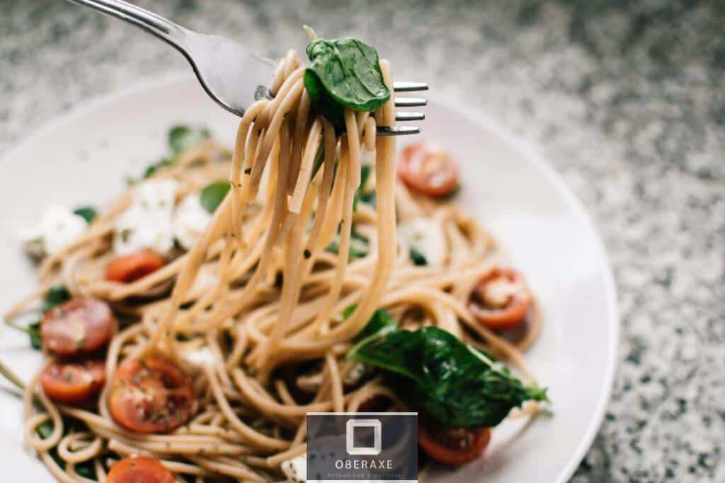 Delicious whole wheat pasta with fresh spinach, cherry tomatoes, and feta cheese in a close-up shot.